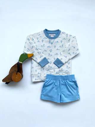 Children's outfit with duck patterned crewneck sweatshirt from TBBC and blue shorts, accompanied by a wooden duck toy