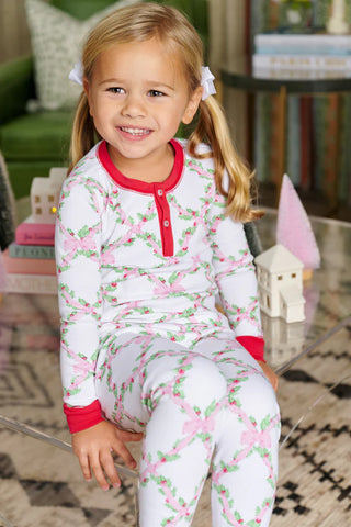 Little girl wearing TBBC Sara Jane's Sweet Dreams Set in Holly Day print with Richmond Red trim, sitting and smiling indoors
