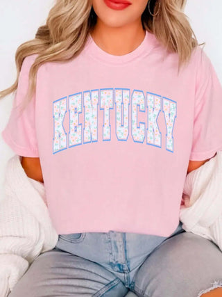 Pink Floral Kentucky Tee—women’s soft t-shirt with bold block “KENTUCKY” letters in pastel floral print and blue outline for Southern charm.