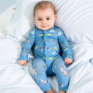 Baby in Magnetic Me Good Knight Convertible Coverall with medieval kingdom print resting on blue and white striped bedding.
