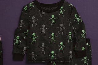 Boys glow-in-the-dark skeleton Halloween pajamas—black bamboo knit two-piece set with spooky print and comfy fit.
