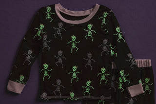 Girls glow-in-the-dark Halloween pajamas with pink skeleton print—cozy bamboo sleep set perfect for spooky season fun.