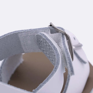 Close-up of white Sun-San Surfer sandal showing Velcro ankle strap and rust-proof buckle detail – water-friendly kids sandal