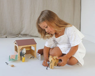 Wooden horse stable playset with ponies, grooming tools, saddle blankets, and barn accessories—perfect for little horse lovers.