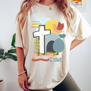 Neutral beige Christian graphic T-shirt featuring “All to Him I Owe” design with cross, empty tomb, and modern abstract Easter artwork.