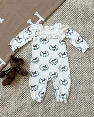 Ivory Darla Day Romper with Highland Horses print, ruffle trim neckline, and elastic cuffs, styled with plush horse toy on woven rug
