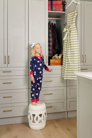 Young girl in TBBC Sutton’s Sweet Dreams Set – Jolly Old St. Nick with Richmond Red trim standing in a festive closet scene.