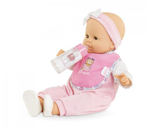 Seated Corolle doll holding the magic milk bottle and wearing the pink bib from the Corolle feeding accessory set.