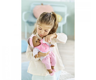 Child feeding a Corolle doll with the magic milk bottle from the teddy bear bib and bottle accessory set for pretend play.