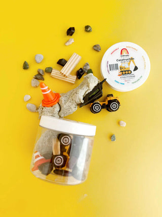 Construction Mini Dough-to-Go Jar with cookies & cream dough, toy trucks, cones, and pebbles for hands-on construction zone play.