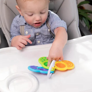 Baby pressing Fat Brain Toys Dimpl Clutch bubbles on a high chair tray, a portable sensory toy with textures and bright colors