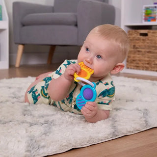 Infant chewing and playing with Fat Brain Toys Dimpl Clutch, a colorful silicone sensory key ring toy for teething and motor skills