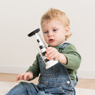 Toddler holding a Fat Brain Flipty toy and watching the black and white rings stack inside clear tube