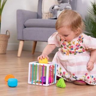 Baby exploring Fat Brain InnyBin with yellow ball shape, practicing problem-solving and fine motor skills through play