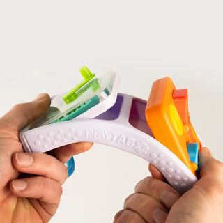 Hands bending the PlayTab Go board, demonstrating its flexibility and how sensory tiles pop out easily for interchangeable play.