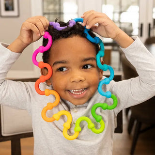 Boy wears a rainbow ring of Plip Links on his head and neck, showing how flexible and playful these popping silicone links can be.