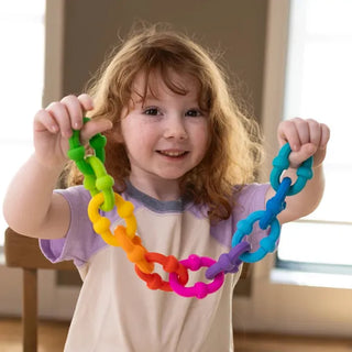 Girl smiles while holding a colorful chain built with Plip Links, a creative sensory toy made for popping, twisting, and building fun.