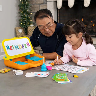 Grandfather and young girl use Pretendables School Desk to learn letters, words, and numbers at the table in a cozy holiday home setting.