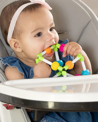 Baby chewing on Quubi sensory cube with bendable elastic bands and bright textured beads, designed for teething and tactile exploration.