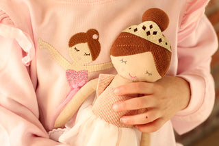 Mud Pie ballerina plush doll in pink tutu held by young girl wearing matching ballerina applique sweatshirt, boutique kids gift and outfit.