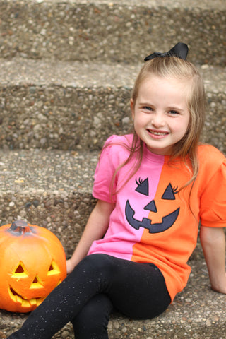 Banana Split jack-o'-lantern Halloween sweatshirt in pink and orange, close-up of little girl smiling in boutique fall outfit.