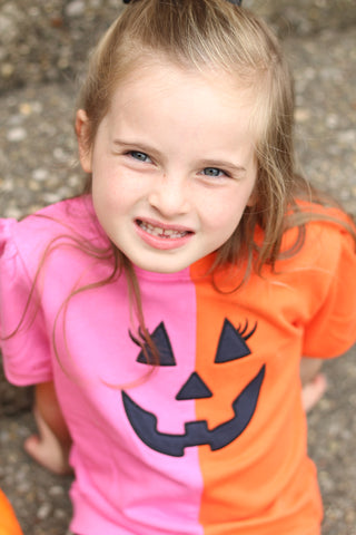 Banana Split jack-o'-lantern Halloween sweatshirt in pink and orange, close-up of little girl smiling in boutique fall outfit.
