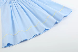 Light blue baby girl smocked dress with Easter embroidery featuring chicks, bunnies, and flowers, short puff sleeves and scalloped trim.