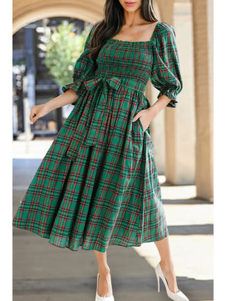 Front view of classic green plaid holiday midi dress from LDC with bow tie waist, puff sleeves, and smocked bodice and white heels.