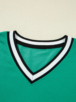 Close-up of green varsity dress neckline showing black and white striped V-neck trim against bright green fabric.
