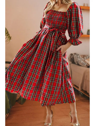 Front view of classic red plaid holiday midi dress from LDC with bow tie waist, puff sleeves, and smocked bodice and gold heels.