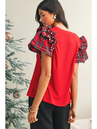 Back view of red holiday tee with plaid ruffle sleeves and pearl accents, shown on a woman in a seasonal setting 