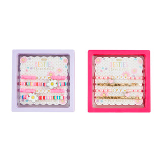 Two sets of hair accessories in pink and purple packaging on a white background
