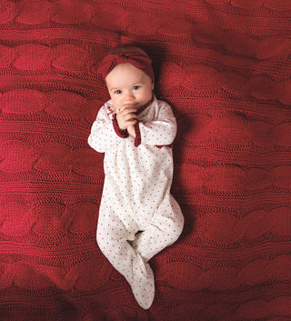 Ivory baby sleeper with red dots, ruffle trim, and bow, paired with matching headband—perfect for baby girl’s first Christmas.