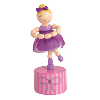 Wooden collapsing toy figure of a ballerina in a purple dress on a pink striped base with a bow on a white background