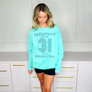 Woman wearing mint Proverbs 31 Motherhood sweatshirt standing sideways showing relaxed fit and comfortable long sleeves.