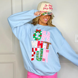 Woman wearing light blue Oh What Fun Christmas sweatshirt with colorful holiday letters, standing indoors and tipping hat