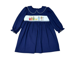 Three Sisters Navy Nativity Girls Dress with smocked nativity embroidery, piped collar, and ruffled sleeves  on soft navy knit fabric.