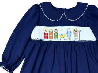 Three Sisters Navy Nativity Girls Dress with nativity embroidery scene including baby Jesus, wisemen, and parents on soft navy knit fabric.