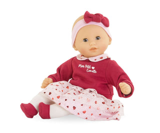 Corolle Bebe Calin Margaux Heart Petals doll sitting upright in red top and heart-print skirt with pink headband.