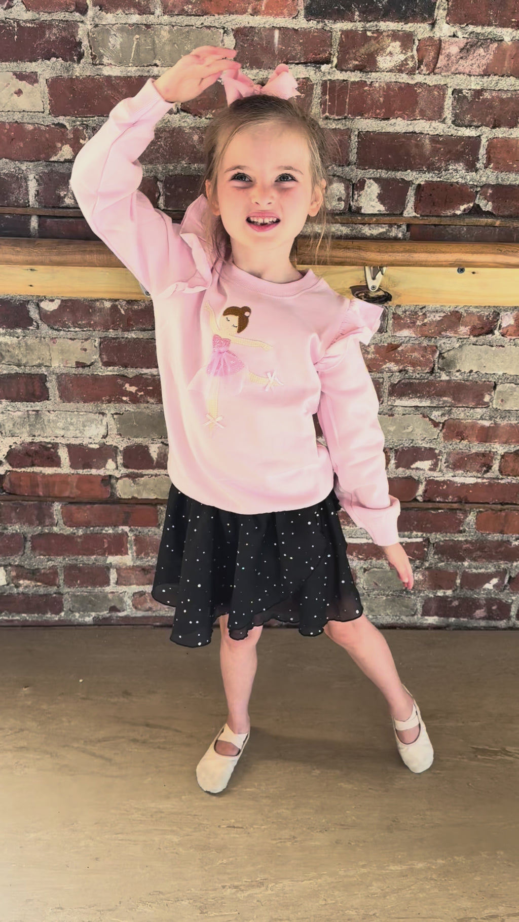 Mud Pie pink ballerina applique sweatshirt with ruffle sleeves, young girl twirling in a dance studio wearing this boutique ballet top.